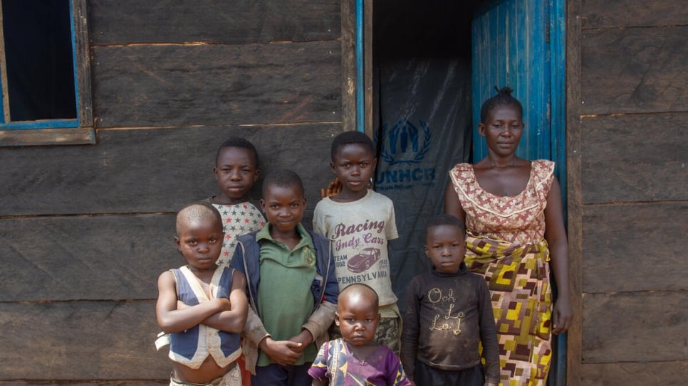 Elodie, a displaced Congolese woman stands with her children outside their durable shelter in Beni, in north-eastern Democratic Republic of the Congo.