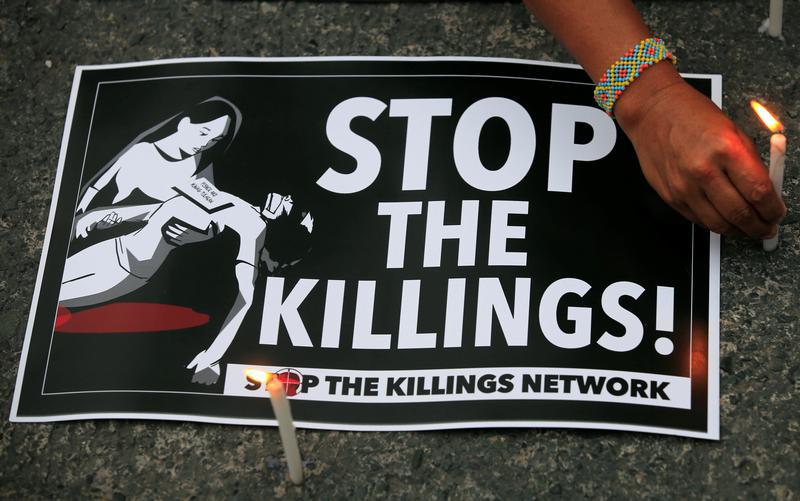 A protester lights candles next to a placard, seeking justice for killings in President Rodrigo Duterte's war on drugs, during a protest in front of the Philippine National Police (PNP) headquarters in Quezon city, Metro Manila, Philippines August 23, 2017.