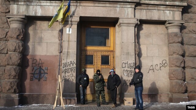 Ukrainian antigovernment protesters stand at the entrance of the Agricultural Ministry building in Kyiv which they occupied late last week.