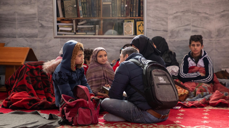 Un membre du personnel du HCR s'entretient avec un garçon et sa famille hébergés dans la mosquée du quartier de Suleiman Al-Halabi à Alep.