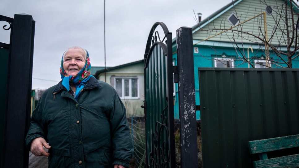 Kateryna pose devant sa maison, qui a été gravement endommagée lors des combats dans le village d'Ozershchyna en mars 2022. 