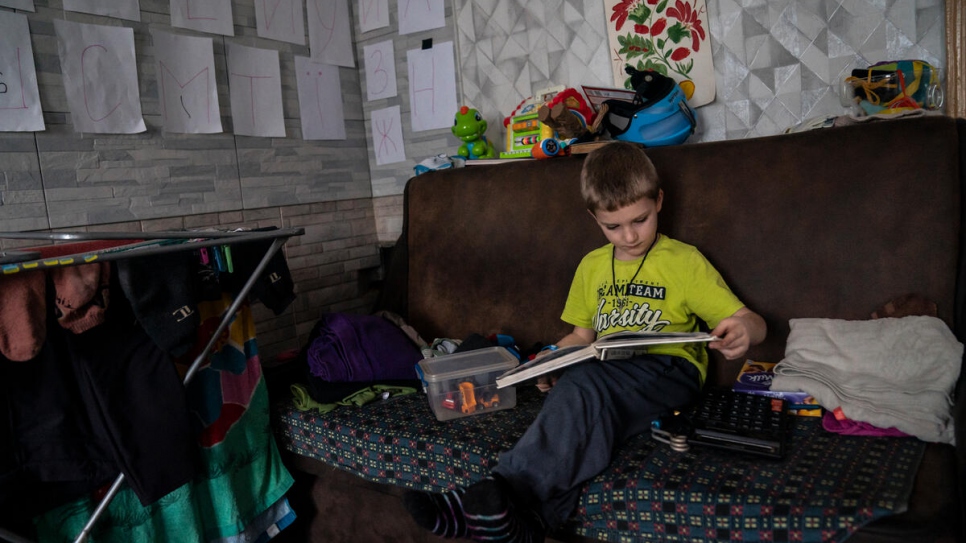 Ivan, 5 ans, feuillette un livre dans la cuisine de ses arrière-grands-parents, où l'alphabet ukrainien a été collé sur les murs pour l'aider à apprendre. 