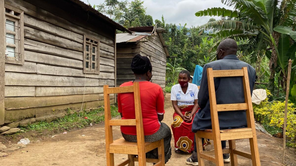 Rosette* (à gauche), une victime de violence sexuelle, et son père en compagnie d'une travailleuse communautaire devant leur maison à Masisi, en République démocratique du Congo. 