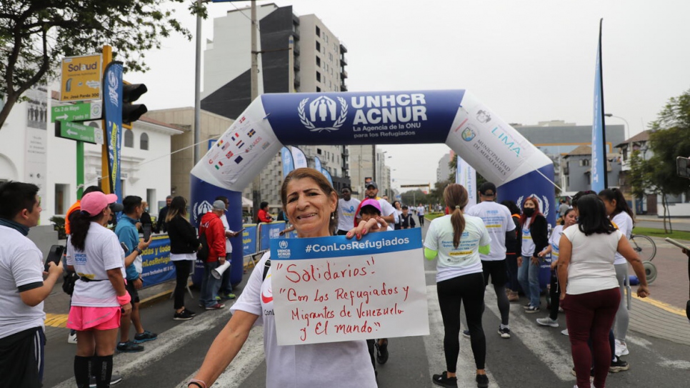 Une participante tient un panneau sur lequel on peut lire : « Solidarité ! Avec les réfugiés et les migrants du Venezuela et du monde entier ». 