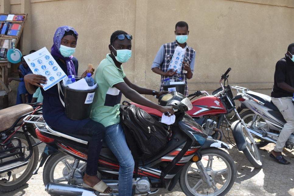 Wearing protective masks, Idriss, 21, and Leila, 25, both refugees from the Central African Republic, travel through N'Djamena, Chad distributing materials to raise awareness about COVID-19.