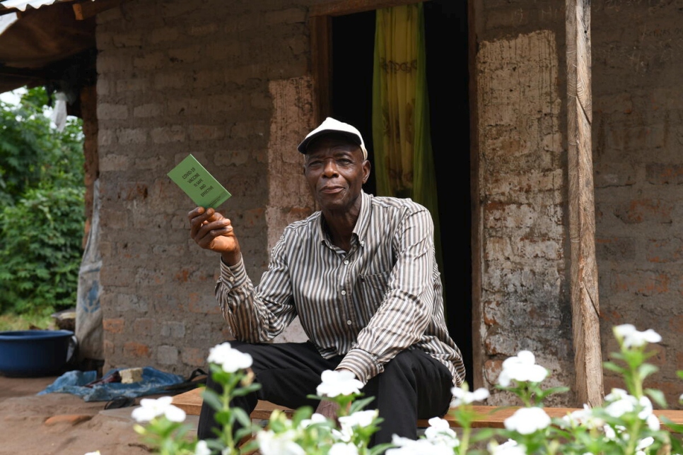 En el asentamiento de refugiados de Adagom, Nigeria, el voluntario Asu Ben Abang, de 65 años, sostiene un folleto en el que se lee "La vacuna de COVID-19 es segura y eficaz".