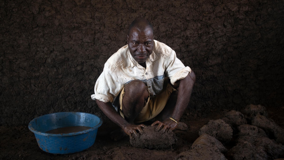 Patrício Alberto Mponda mezcla el agua con el barro que se utilizará para construir las paredes de su nueva casa en el asentamiento de personas desplazadas de Corrane.