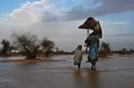 A refugee family carrying their belongings out of the water after their makeshift shelter was flooded when the first heavy rains near Bahai swelled the seasonal riverbed. The flooded-out refugees were immediately transferred to a new camp that had just opened to receive them. (July 14, 2004)