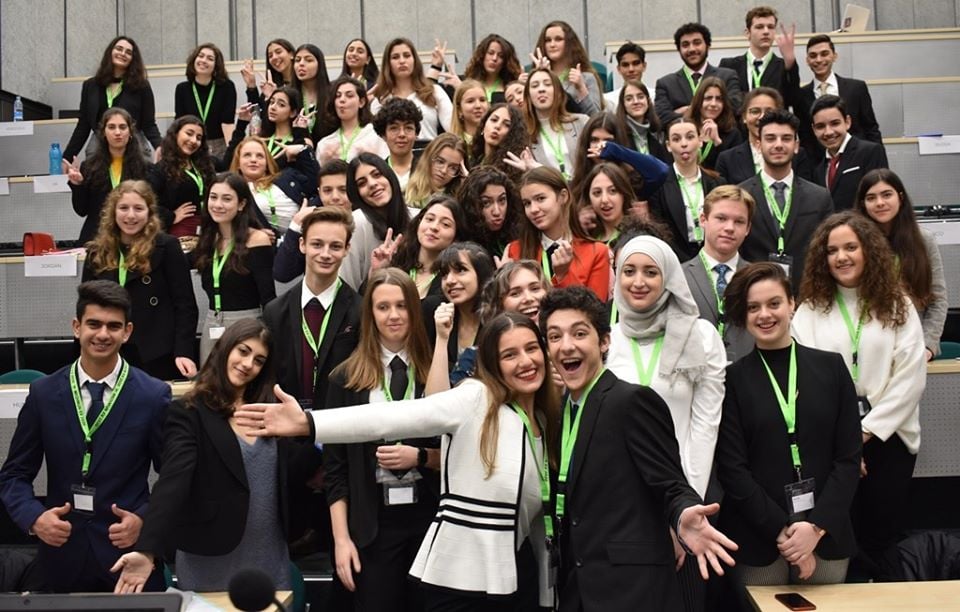 A group of young people in a conference room smile for the camera 