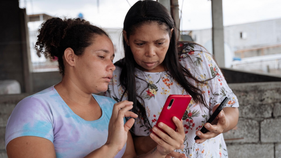 Desiree shows her neighbour, Maigualida, how to use the new internet service.