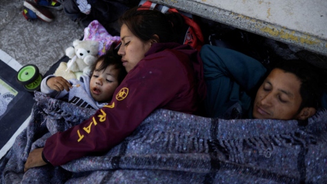 A family rests in the Mexican city of Rio Frio de Juarezas as they journey towards Mexico City, on 11 December
