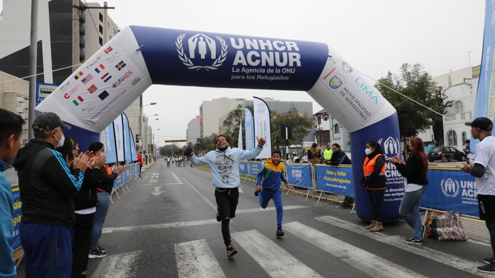 Two runners with big smiles on their faces celebrate reaching the finish line.