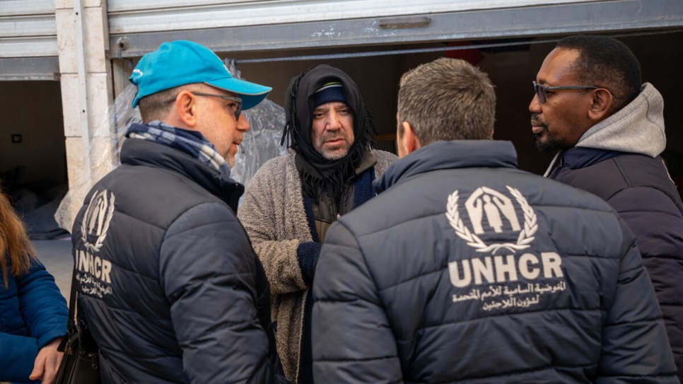 Mazen (centre), a father of four from Aleppo whose home was damaged by the earthquakes, meets UNHCR staff outside the retail unit in Al-Harir souq where his family are staying.