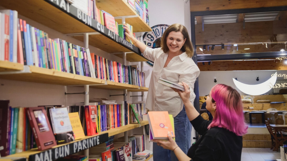 Ekaterina and Stefania stack books at the Seneca Anticafé bookshop and shared workspace where they both work. 