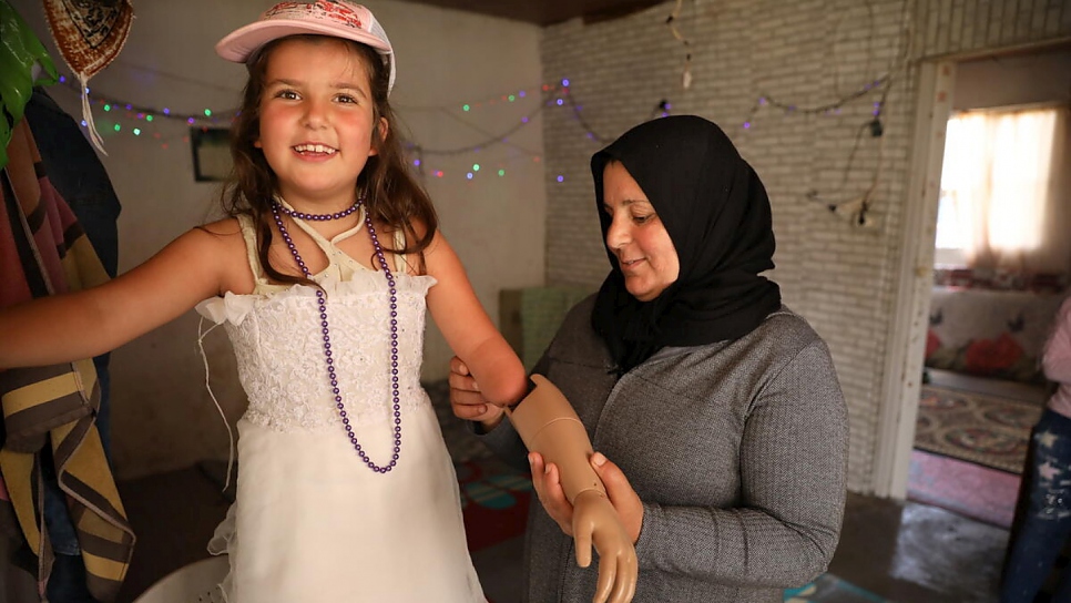 Safiyah helps Sarah to attach her prosthetic arm, which was provided by Lebanese NGO Bionic Family. 