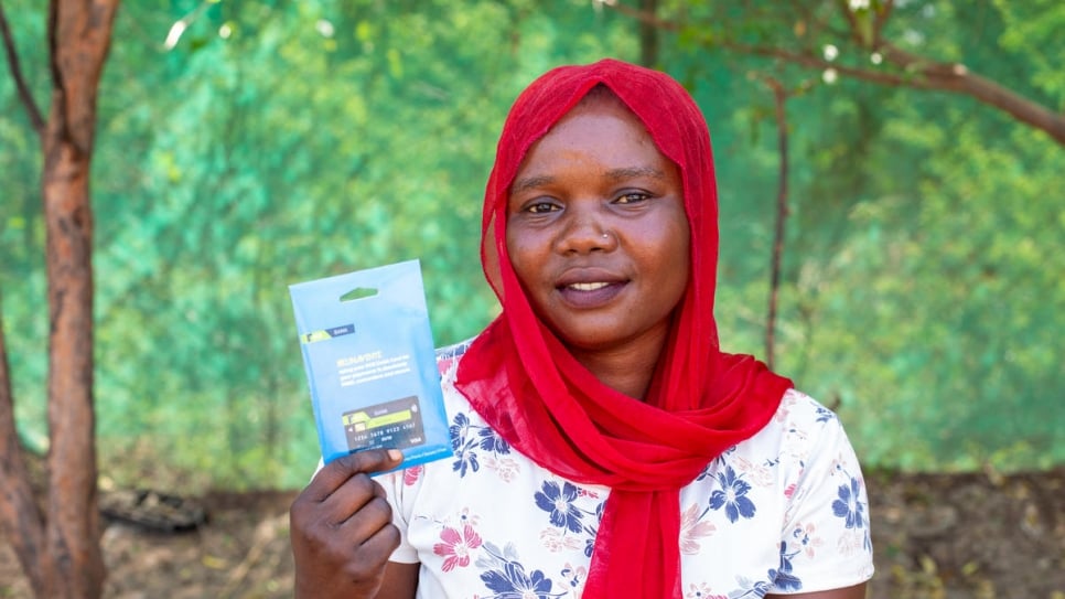 A refugee holds her recently issued ATM card, which she will use to buy soap and sanitary items through UNHCR's Cash-Based Intervention scheme at Kakuma camp.
