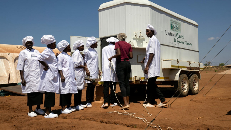 The class uses extension cords to plug electric mixers and other appliances into a truck hooked up to the settlement's electricity system. 