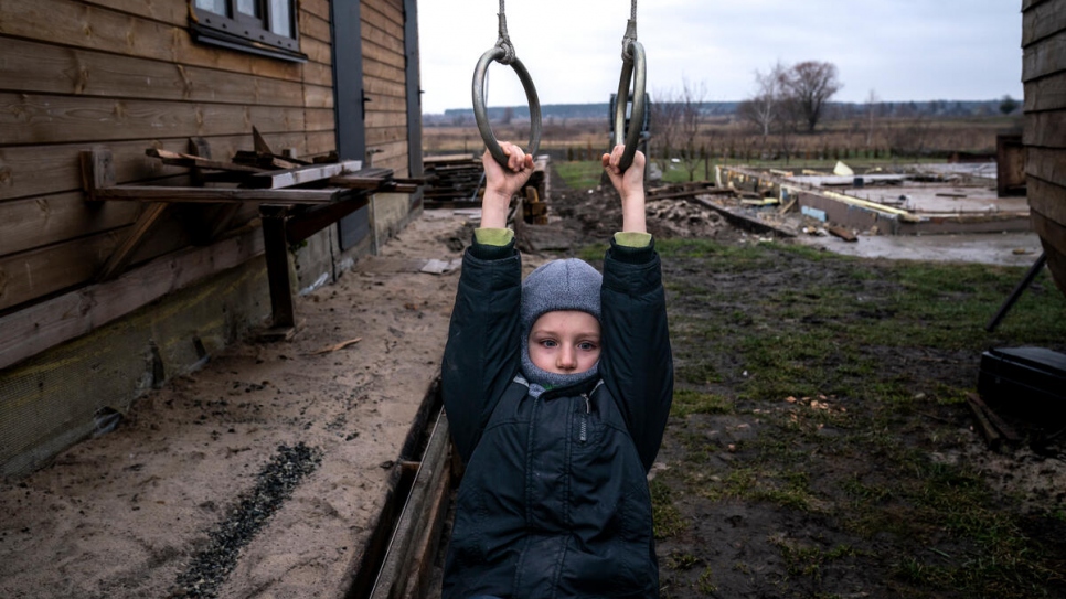 Ivan plays on a swing his father built for him in the yard of what used to be their home.