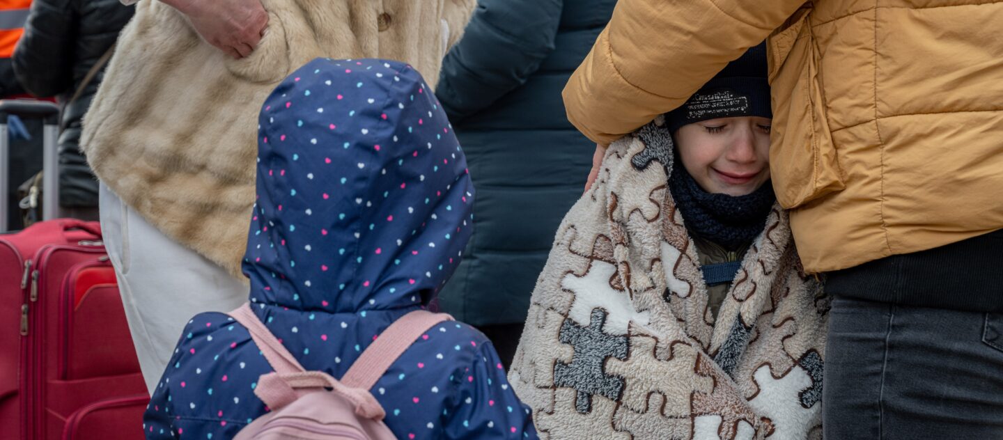 Une mère tente de garder ses enfants au chaud lors du passage de la frontière moldave, en mars 2022. © UNHCR/Mihai von Eremia