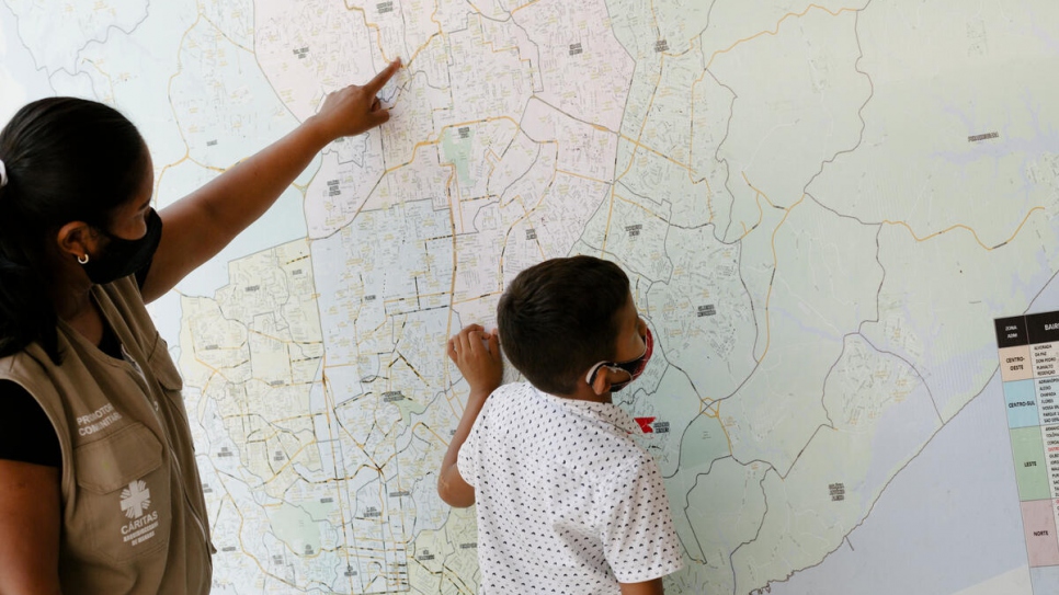 Lucetti and her 8-year-old Keiver examine a giant map of Manaus that hangs in her workplace, the UNHCR partner Caritas.
