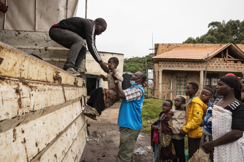 Jimmy Ogwang, een UNHCR-medewerker die actief is op het terrein, helpt nieuwkomers bij de grensovergang in Bunagana bij het instappen in een vrachtwagen naar het Nyakabanda transitcentrum in Kisoro, Oeganda.