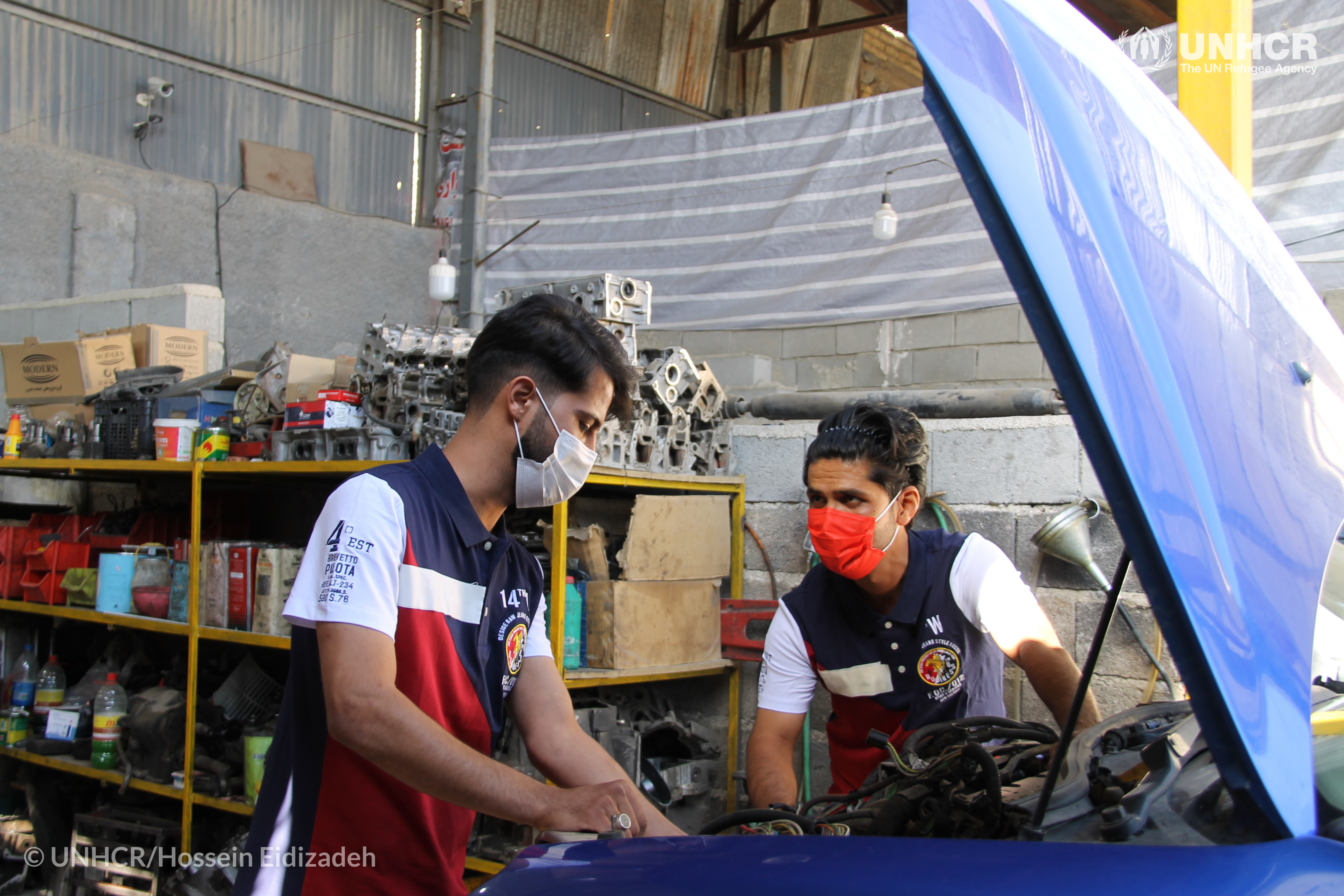 Abbas Balkh (rechts), een 31-jarige Afghaanse vluchteling, en Danial Hosseini (links), een 25-jarige Iraniër, werken aan het repareren van een auto in hun auto-reparatiewerkplaats in Iran. De twee ondernemers hebben hun winkel onlangs uitgebreid dankzij de steun van de UNHCR. ©UNHCR/Hossein Eidizadeh