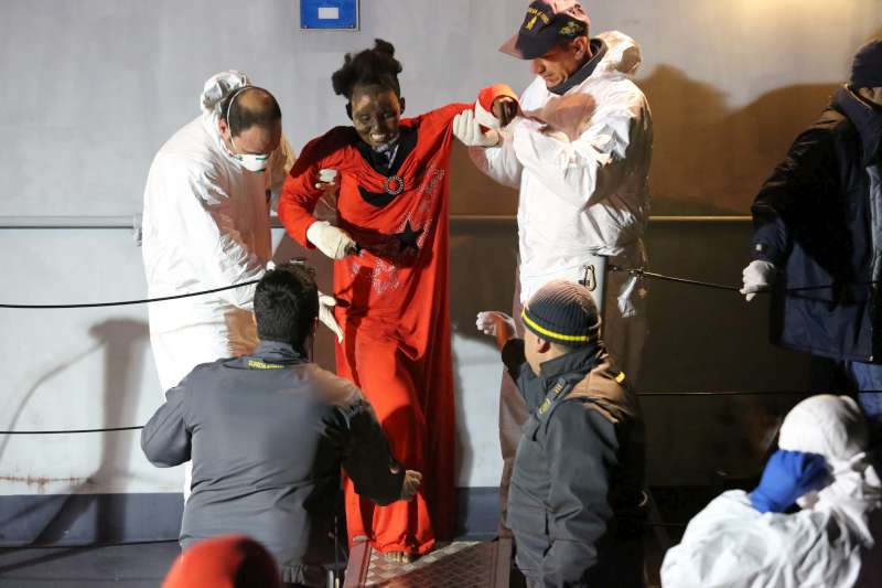 A woman with severe burns to her face is helped off of an Italian Coastguard vessel in Lampedusa. She was plucked from a dinghy in the Mediterranean and later taken by helicopter for treatment.  