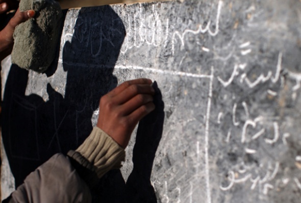 An Afghan boy writes on a chalkboard at a rural school. (Photo: Spencer Platt/Getty Images)