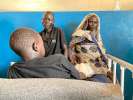 Parents Hissen Awad Mohammed (L) and Haja Ibrahim watch over their inj...