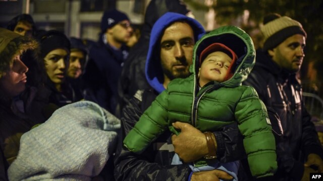 A man carrying his child waits with other migrants and refugees to be registered at a refugee center in Presevo, Serbia, on October 25.