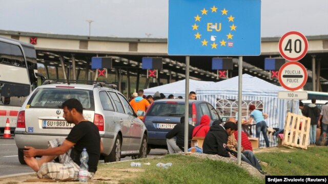 Migrants gather near a European Union sign at the Croatia-Slovenia border crossing at Bregana, Croatia, on September 19.