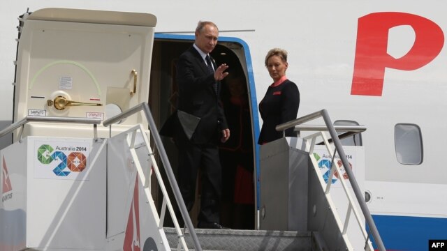Russian President Vladimir Putin waves as he boards his plane to depart from the G20 summit in Brisbane, Australia, on November 16.