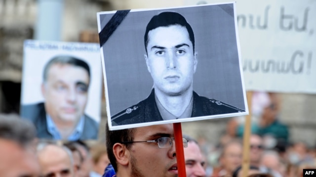 Demonstrators in Hungary hold up a photo of Armenian Army Lieutenant Gurgen Margarian (right) in front of the parliament building in Budapest on September 4 at a protest against the repatriation of Ramil Safarov.