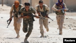 Syrian Kurdish fighters from the People's Protection Units (YPG) run across a street in Raqqa on July 3.