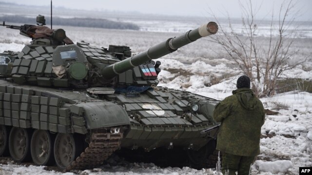 A pro-Russian separatist stands in front of a tank at a checkpoint in Yenakieve, 25 kilometers from the eastern town of Debaltseve, on January 29.