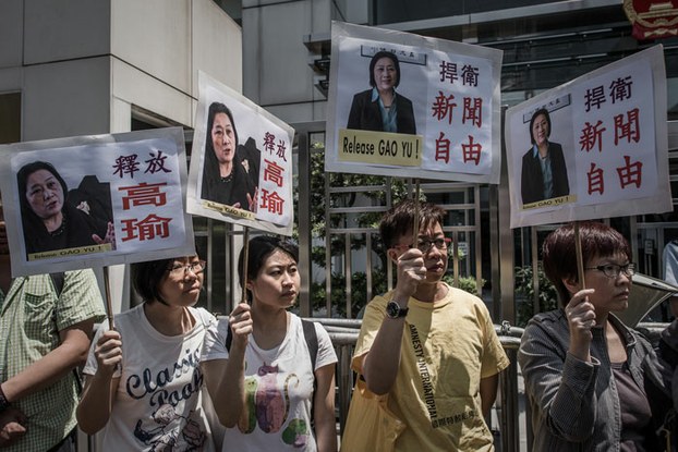 Demonstrators hold placards showing portraits of Chinese journalist Gao Yu during a protest in support of her outside the China liaison office in Hong Kong, April 17, 2015.