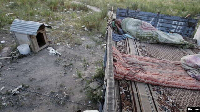 A migrant worker sleeps on top of a shelter outside Moscow.