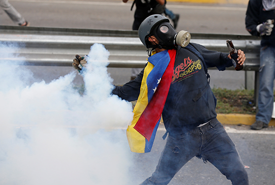A protester throws a tear gas canister back at police in Caracas, May 2, 2017. (Reuters/Carlos Garcia Rawlins)