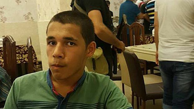A Uyghur student sits at a restaurant table in Cairo while police detain others behind him.