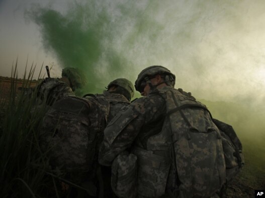 U.S. Army soldiers shield themselves from rotor wash as they use green smoke to mark a landing zone for a Blackhawk helicopter after an operation to disrupt weapons smuggling in Istaqlal, Iraq, in August.