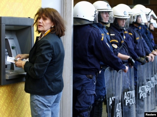 A woman makes a transaction at an ATM during a rally against austerity measures outside the Finance Ministry in Athens on April 29.