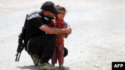 An Iraqi soldier helps a displaced girl near Mosul.