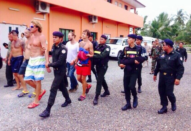 Military police officers lead a group of Russian nationals to an airport in Sihanoukville, before flying them to Phnom Penh where they will await deportation, May 15, 2015.