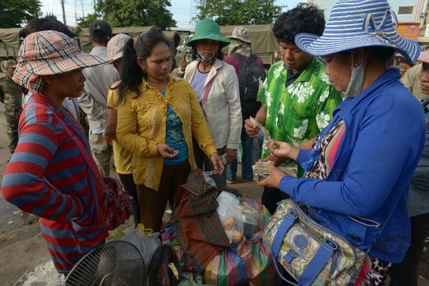 Migrant construction worker Chim Phon (2nd R) changes Thai baht to Cambodian riel currency as he arrives in the Cambodian city of Poipet on the Thai-Cambodian border, June 17, 2014.
