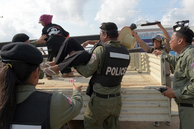 A Cambodian policeman loads a protester into the back of a police truck during a demonstration in Phnom Penh demanding the release of detained rights defenders, May 9, 2016.