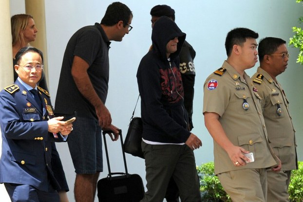 Refugee is escorted from Phnom Penh International Airport after transfer from Australia, June 4, 2015.
