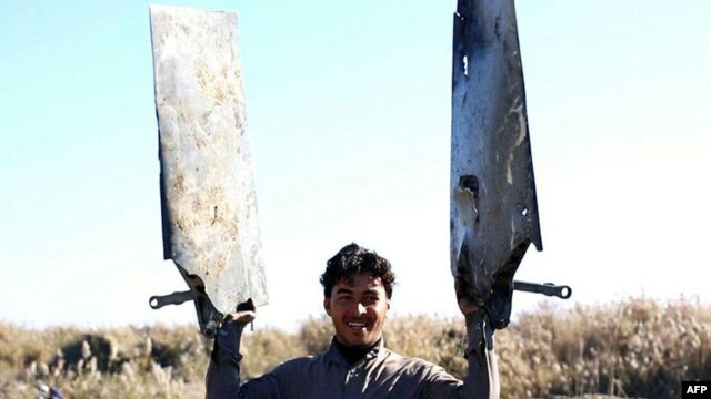 A video grab purportedly showing an Islamic State fighter displaying pieces of a warplane from the US-led coalition that crashed near Raqqa city in Syria.