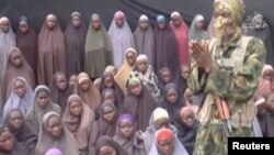 A still image from a video posted by the Nigerian Islamist militant group Boko Haram, showing a masked man talking to dozens of girls who had been kidnapped in the town of Chibok in 2014.