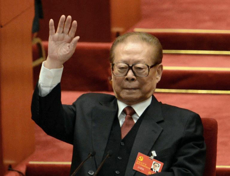 Former Chinese president Jiang Zemin raises his hands to vote for a report at the closing of a Chinese Communist Party Congress at the Great Hall of the People in Beijing, Nov. 14, 2012.