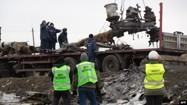 Members of the Dutch recovery and export team watch as Malaysia Airlines Flight 17 wreckage is loaded onto a truck near Hrabove in eastern Ukraine on November 16.